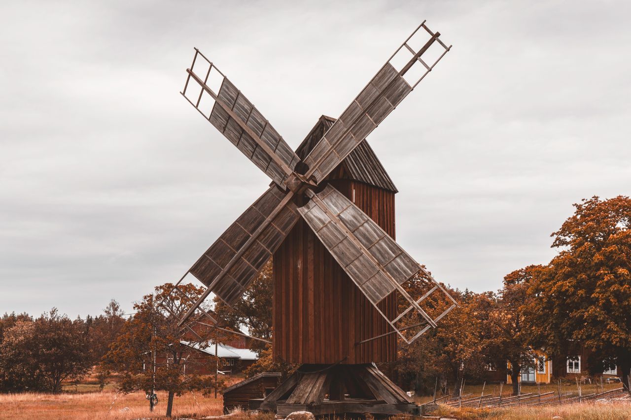 Charming view of a vintage wooden windmill surrounded by autumn foliage in Åland Islands countryside.